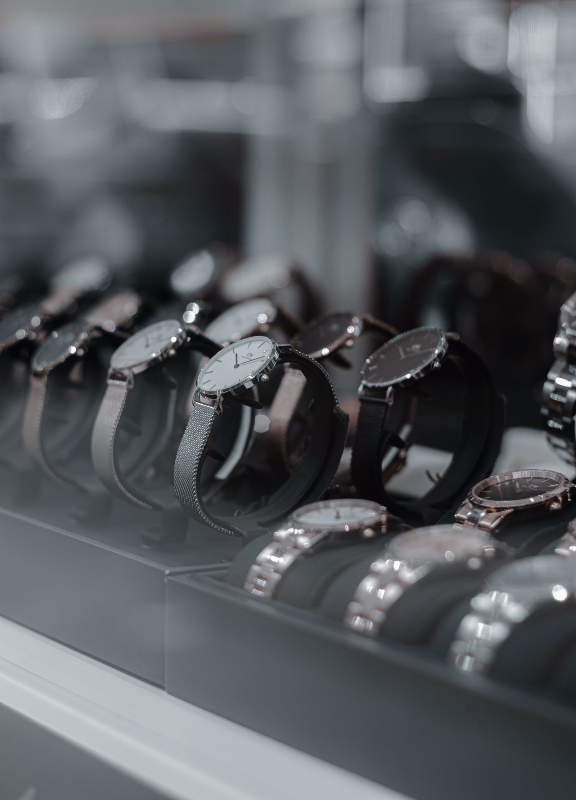 Collection of modern wristwatches displayed in a showroom, featuring various strap styles and minimalist watch faces.